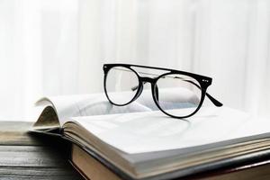 Reading glasses put on open book beside the window photo