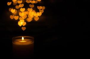 Aromatic candle with flame and love shape bokeh on dark background for Thanks giving and Christmas day. photo