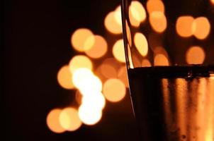 A glass of wine has the shadow of yellow and orange bokeh light on it which isolated on dark color background photo