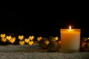 Candle lights and Christmas ornaments with golden love shape bokeh lights. Christmas and New year concept. photo