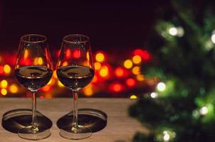 Two glasses of Rose wine on wooden table with Christmas tree and colorful bokeh light background. photo