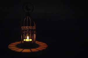 Beautiful Lantern that have moon symbol on top that have light from candle shining on wooden tray with dark background. photo