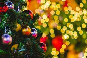 Selective focus of baubles hanging on Christmas tree with colorful bokeh background. photo