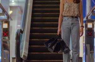 Woman holding shopping bags with shopping mall escalator background. Black Friday sale concept. photo