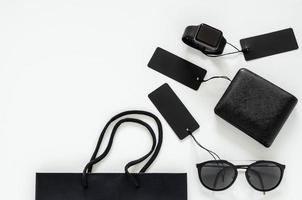 Flat lay of men stuffs - black wallet, sunglasses, smart watch, price tags and shopping bag on white background for Black Friday sale concept. photo