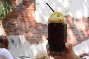 el café espresso con cubitos de hielo que mezclan refrescos endulzados para disfrutar del clima cálido del verano con el fondo de un café con una vieja pared de ladrillos foto