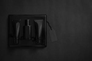 A black box of perfume with blank black price tag on black background. Black Friday concept. photo