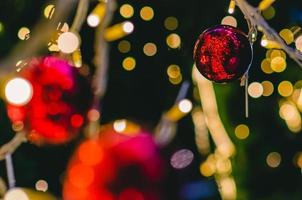 adorno rojo en el árbol de Navidad con fondo de luces bokeh de colores. foto