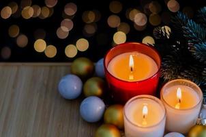 enfoque y velas borrosas puestas en una bandeja de madera con árbol de navidad y adornos con fondo de luz bokeh. foto