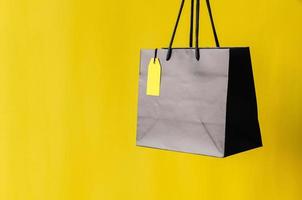 bolsa de compras negra con etiqueta de precio amarilla en blanco con fondo amarillo para el concepto de venta de compras de viernes negro. foto