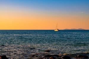 superficie del mar y horizonte con yate en la hermosa puesta de sol con vistas al mar en el fondo foto