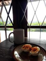 Breakfast with 2 pieces of boiled eggs sprinkled with chili powder and salt on top, also a glass of water photo