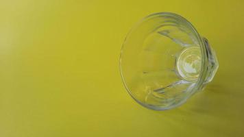 un vaso transparente sobre un fondo amarillo foto