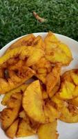 Details of fried cassava on a white plate, a snack from Indonesia made from cassava on a green grass background photo