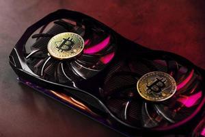 On the fans of a powerful video card, the coins of the Bitcoin cryptocurrency with a red backlight are displayed. photo