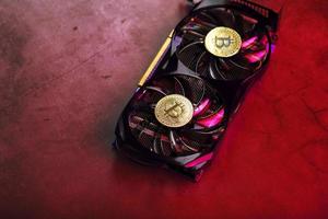 On the fans of a powerful video card, the coins of the Bitcoin cryptocurrency with a red backlight are displayed. photo