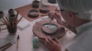 Aziatisch ouderen vrouw genieten van pottenbakkerij werk Bij huis. een vrouw keramist is maken nieuw pottenbakkerij in een studio video