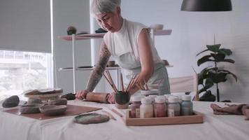 mulher idosa asiática desfrutando do trabalho de cerâmica em casa. uma ceramista feminina está fazendo nova cerâmica em um estúdio video