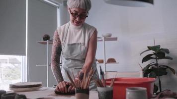 mulher idosa asiática desfrutando do trabalho de cerâmica em casa. uma ceramista feminina está fazendo nova cerâmica em um estúdio video