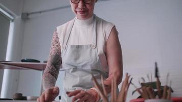 Asian elderly woman enjoying pottery work at home. A female ceramicist is making new pottery in a studio video