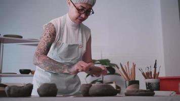 asiatico anziano donna godendo ceramica opera a casa. un' femmina ceramista è fabbricazione nuovo ceramica nel un' studio video