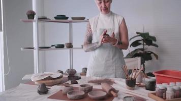 asiatico anziano donna godendo ceramica opera a casa. un' femmina ceramista è fabbricazione nuovo ceramica nel un' studio video