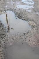 Photo of a fragment of a destroyed road with large puddles in rainy weather