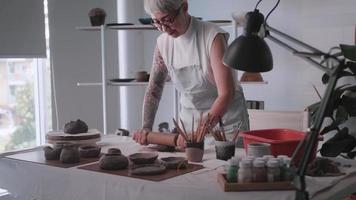 mulher idosa asiática desfrutando do trabalho de cerâmica em casa. uma ceramista feminina está fazendo nova cerâmica em um estúdio video