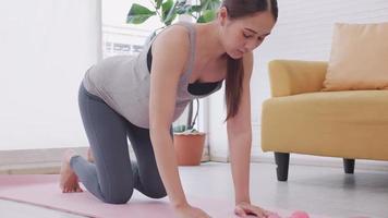 hermosa joven asiática embarazada en ropa deportiva está haciendo yoga en casa.