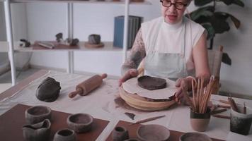 asiatisk äldre kvinna njuter krukmakeri arbete på Hem. en kvinna keramiker är framställning ny krukmakeri i en studio