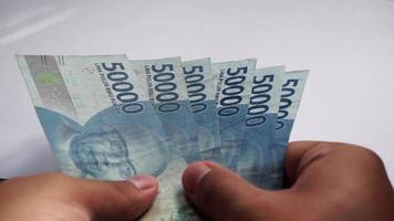 mão contando dinheiro de 10.000 e 50.000 rupias. rupia é a moeda oficial da Indonésia para pagamento. video