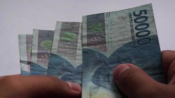 hand- tellen 10000 en 50000 roepia geld. roepia is Indonesië officieel valuta voor betaling. video