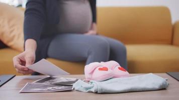 Pregnant woman is preparing clothes for her newborn baby. video