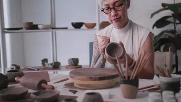 asiatische ältere frau, die zu hause töpferarbeit genießt. Eine Keramikerin stellt in einem Studio neue Töpferwaren her video