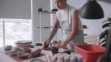 asiatisk äldre kvinna njuter krukmakeri arbete på Hem. en kvinna keramiker är framställning ny krukmakeri i en studio video