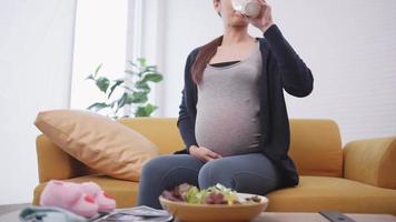 feliz mulher grávida asiática come comida saudável para o feto. video