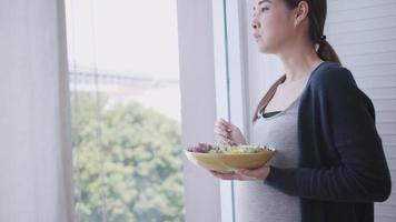 feliz mujer asiática embarazada come alimentos saludables para su bebé por nacer. video