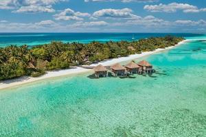 increíble playa de la isla. maldivas desde vista aérea tranquilo paisaje tropical junto al mar con palmeras en la playa de arena blanca. costa de naturaleza exótica, isla de resort de lujo. hermoso turismo de vacaciones de verano foto