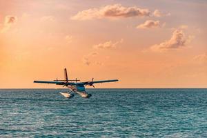 escena exótica con hidroavión en el desembarco marítimo de maldivas. hidroavión aterrizando en el mar al atardecer. vacaciones o vacaciones en el fondo del concepto de maldivas. transporte aéreo, hidroavión de aterrizaje en la costa del amanecer foto