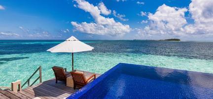 Beautiful panoramic travel sea landscape, luxury romantic beach holidays for honeymoon couple, tropical vacation in luxurious hotel resort. Amazing water villa with chairs and umbrella, infinity pool