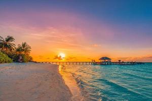 Fantastic closeup view of sunset beach. Tropical island beach landscape exotic palm coast, wooden pier. Summer romantic vacation, holiday amazing nature scenic. Relax paradise, beautiful sunrise sky