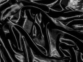 Black satin texture background with liquid wave or wavy folds. Wallpaper design photo