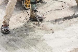 Construction worker using jackhammer drilling concrete surface photo