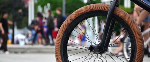 A BMX bike wheel against the backdrop of a blurred street with cycling riders. Extreme Sports Concept photo