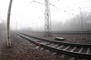 The Ukrainian suburban train rushes along the railway in a misty morning. Fisheye photo with increased distortion