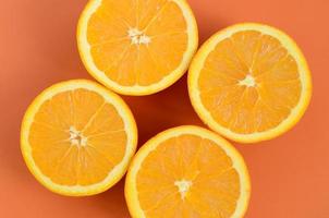 Top view of a several orange fruit slices on bright background in orange color. A saturated citrus texture image photo