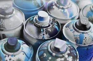 A lot of used spray cans of paint close-up. Dirty and smeared cans for drawing graffiti. The concept of a sweeping and careless drawing of paint. Creative art image photo