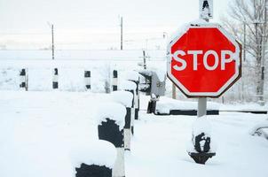 Stop. Red road sign is located on the motorway crossing the railway line in winter season photo