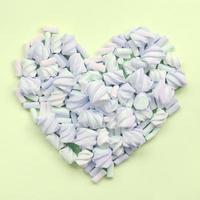 Colorful marshmallow laid out on lime and pink paper background. pastel creative textured heart photo