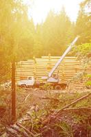 el proceso de construcción de una casa de madera a partir de vigas de madera de forma cilíndrica. grúa en condiciones de trabajo foto